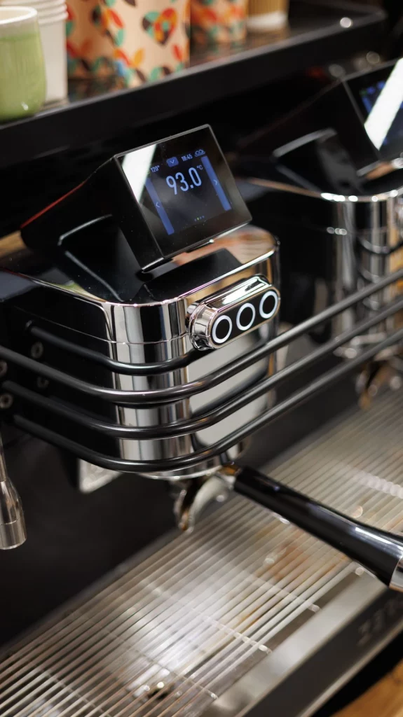 Máquina de café espresso profesional con pantalla digital de temperatura en tienda de café de especialidad.