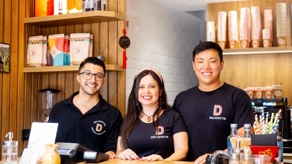 Equipo de baristas de la tienda de café de especialidad sonriendo detrás del mostrador.
